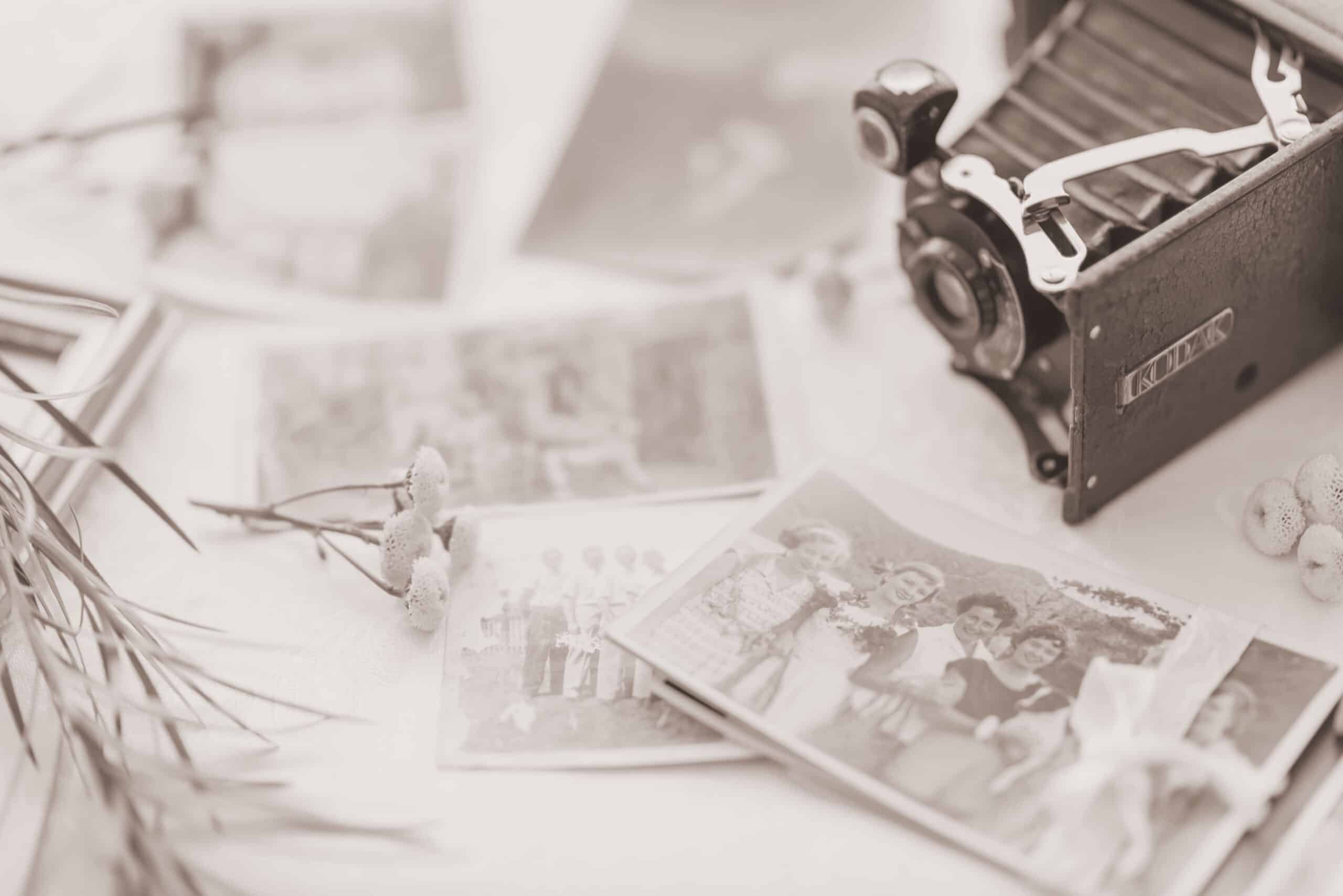 Old family photographs and a vintage camera laid out on a table
